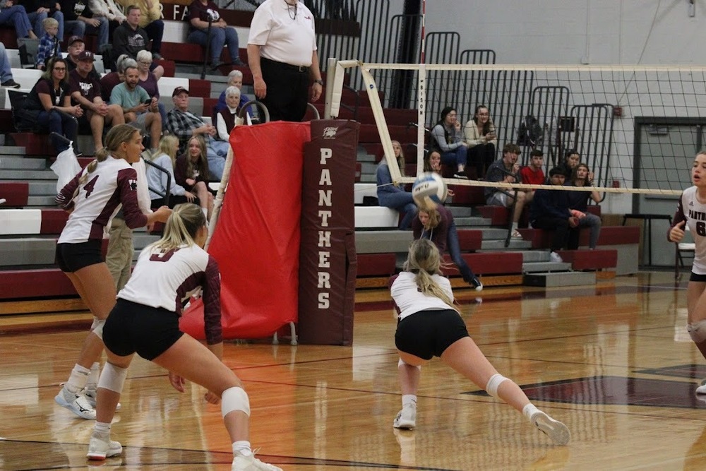 A Panther volleyball player goes for a dig as other players watch 