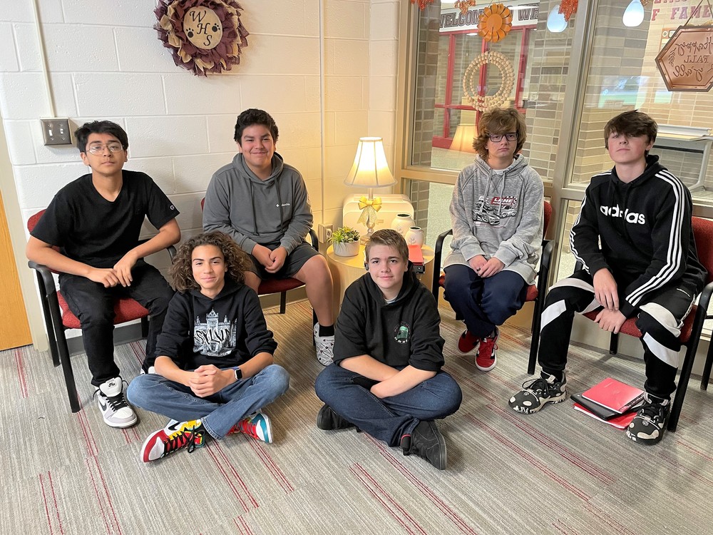 Four high school student members of the Esports team seated in chairs and two sit on the floor.