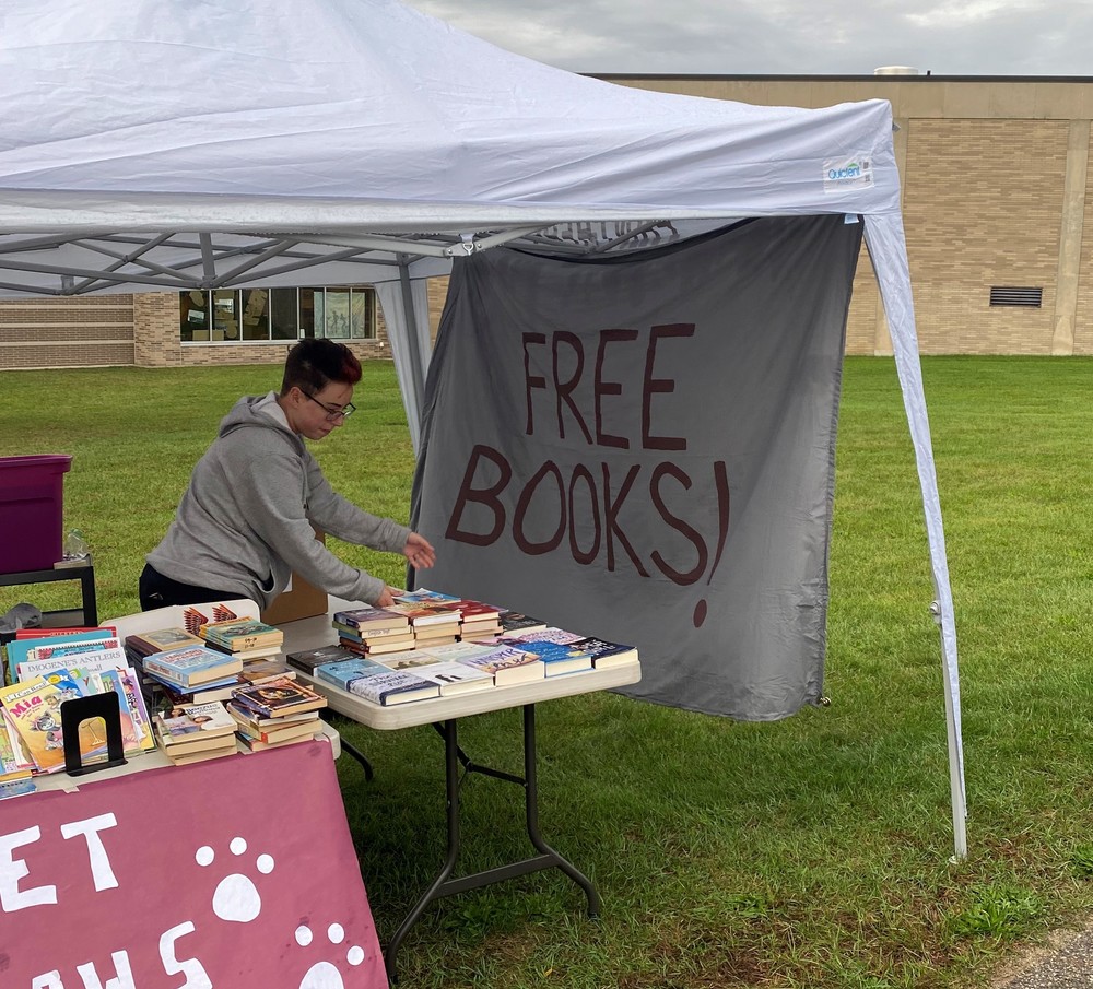 Book Givaway tent with large "Free Books!" Sign and staff member