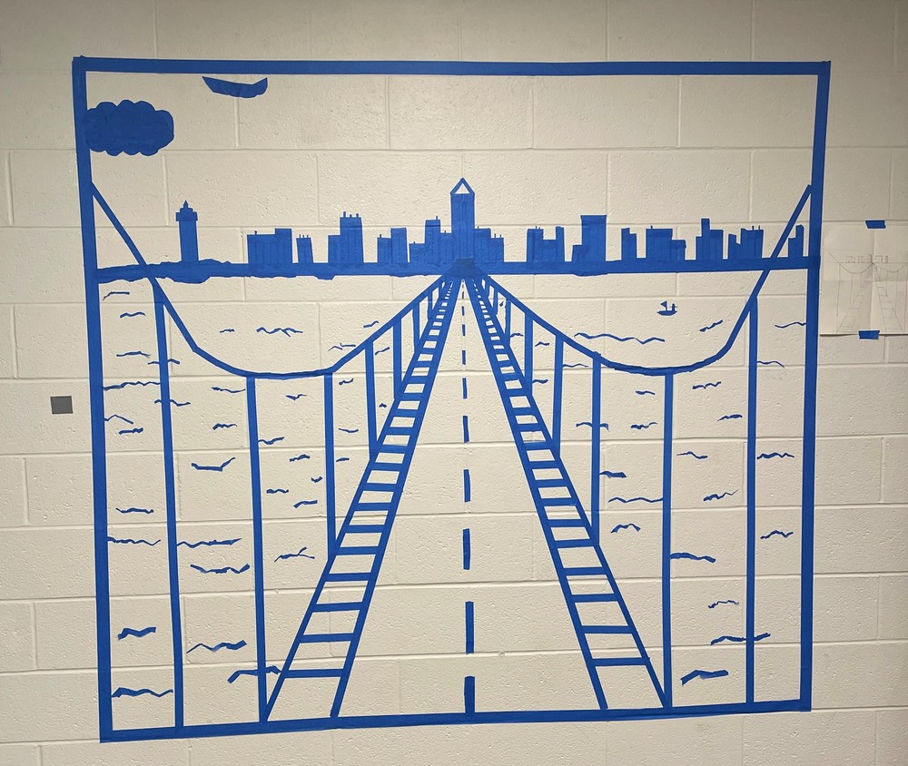 A suspension bridge with a road on it leads to a cityscape in the distance.  The image is created with blue masking tape on a white wall