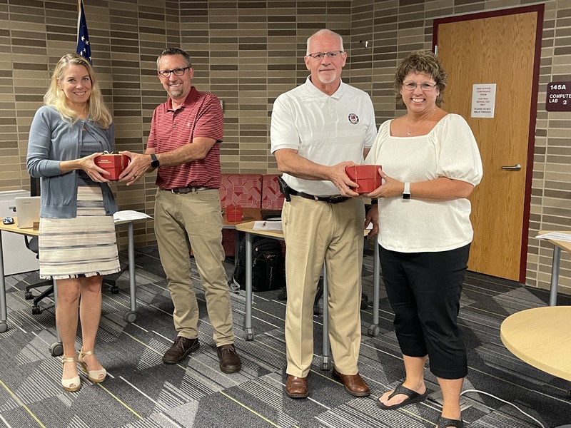 Retirees Heather Winter and Sherry Cullitan receive Golden Apples from School Board Secretary John Oliphant and Board President Bill Spaulding