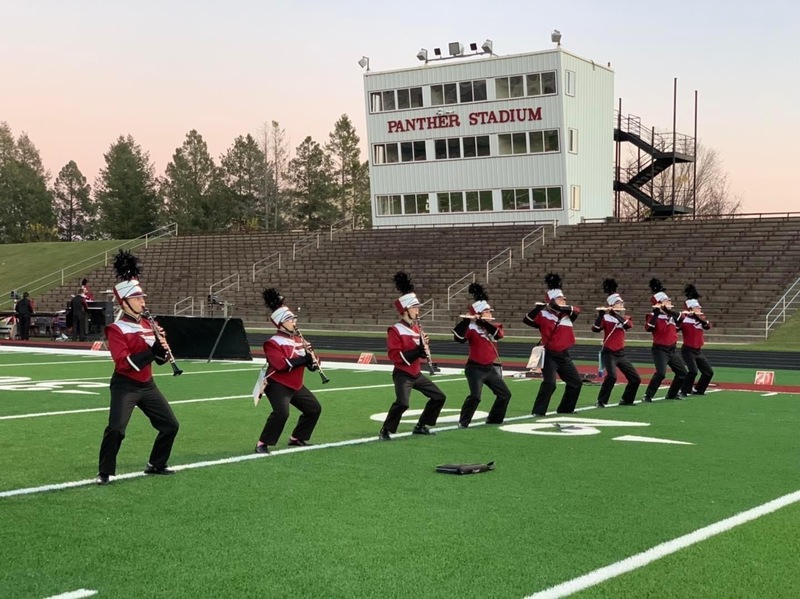 members of the band's flute and clarinet sections perform on the football field in full uniform